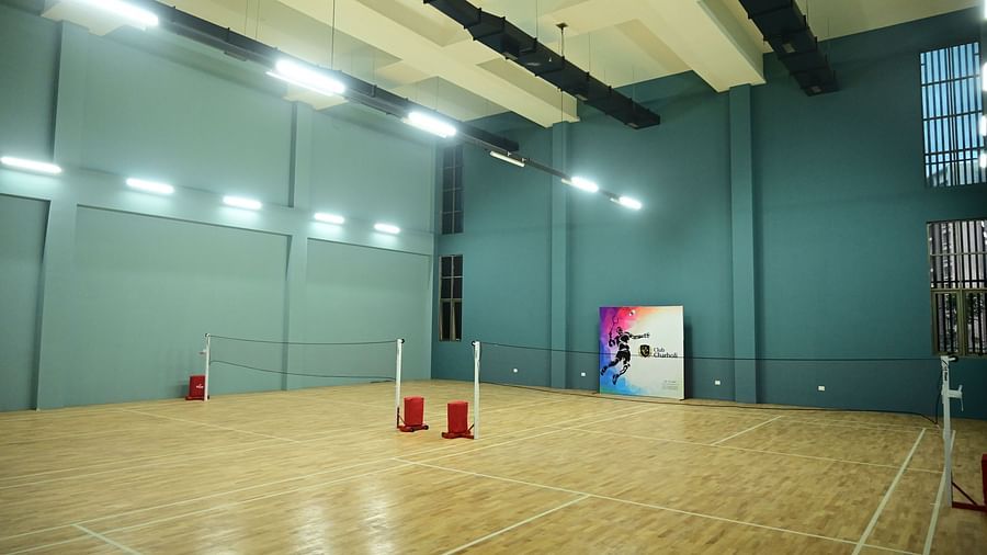 an indoor badminton court with teal coloured walls at club charholi, pune